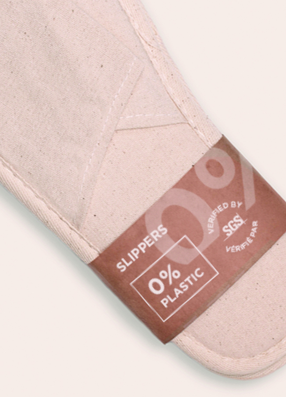 A close-up of a fabric slipper featuring a label that states "0% Plastic" and "Verified by SGS."
