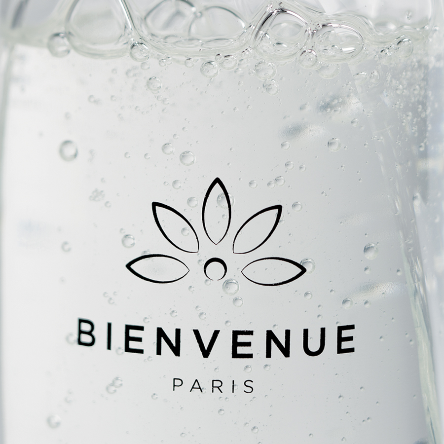 Close-up of a bottle of sparkling water with the label "BIENVENUE PARIS" and bubbles visible in the liquid.