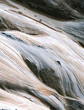 Abstract patterns of swirling browns, grays, and whites resemble flowing water or marbled textures.