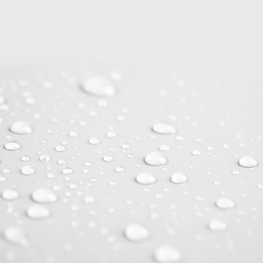 Close-up of clear water droplets scattered on a light gray surface, creating a soft, smooth texture.