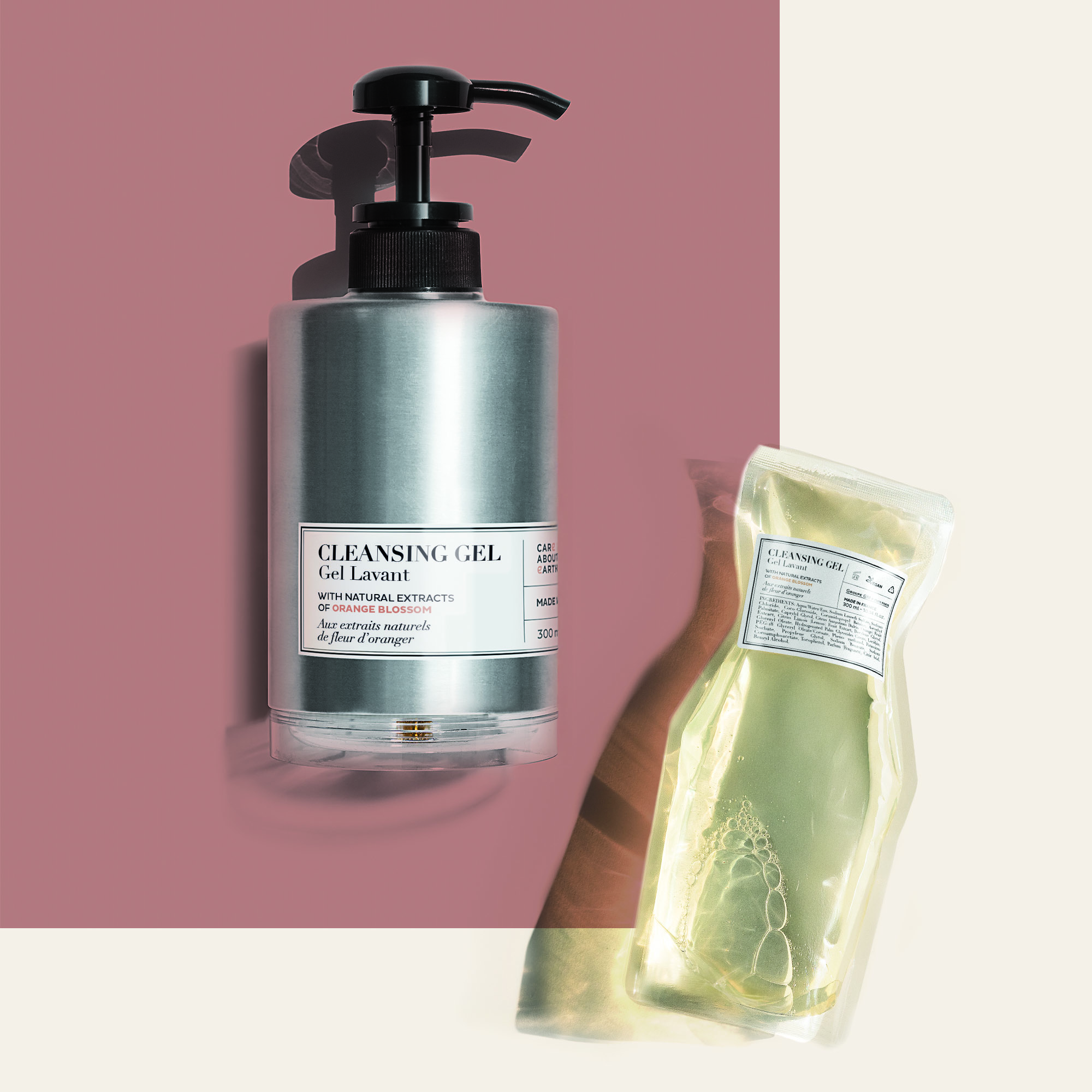 A sleek silver pump bottle of cleansing gel alongside a transparent package containing a green gel product, set against a soft pink and cream backdrop.