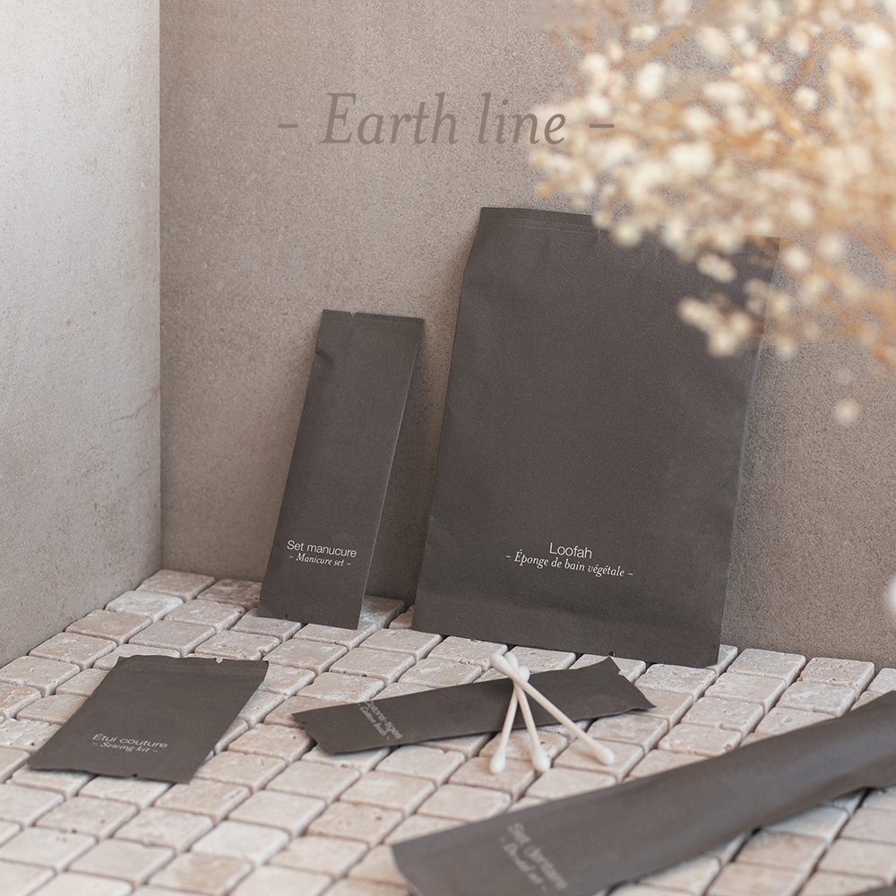 A collection of eco-friendly packaging, including bags and small pouches, displayed on a textured surface with a minimalist design and subtle branding.