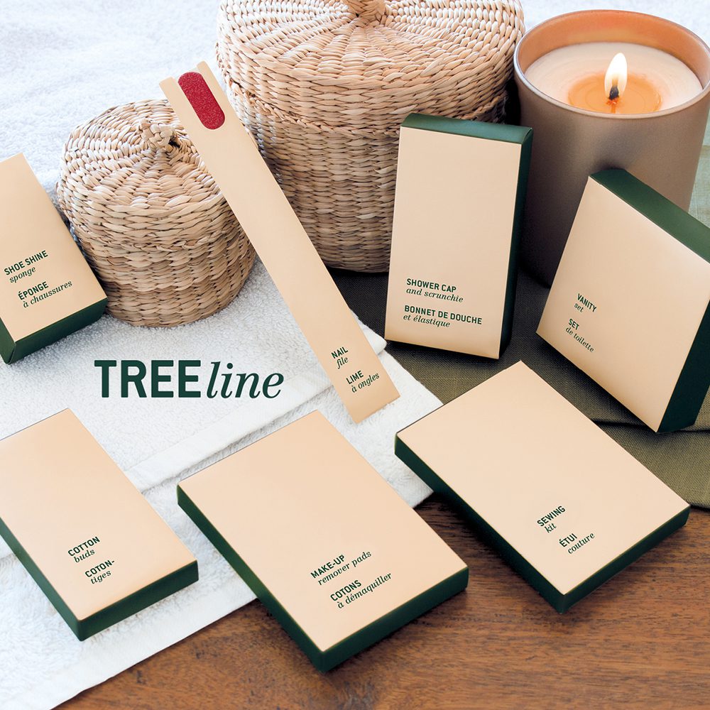 A collection of eco-friendly personal care products arranged on a table, including shower caps, makeup wipes, and cotton swabs, alongside a lit candle and woven baskets.