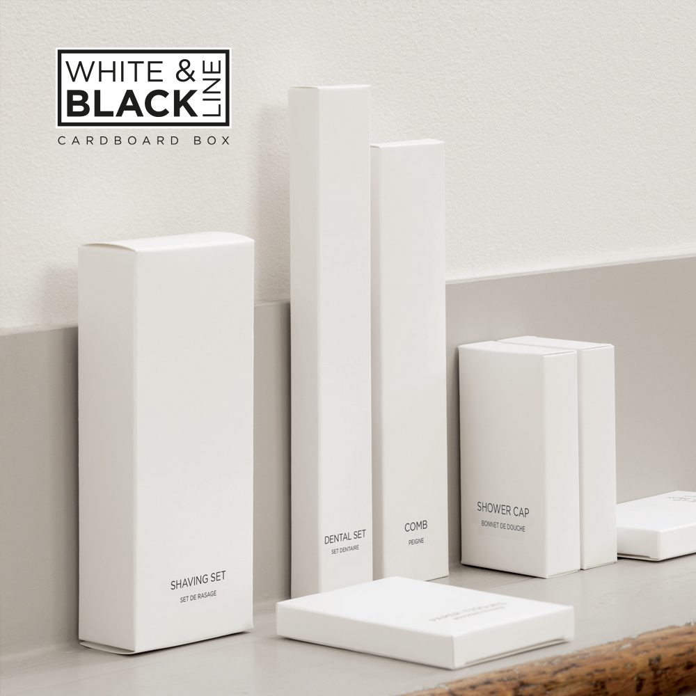 A collection of minimalistic, white cardboard boxes for grooming products displayed on a countertop, including items labeled "Shaving Set," "Dental Set," "Comb," and "Shower Cap."