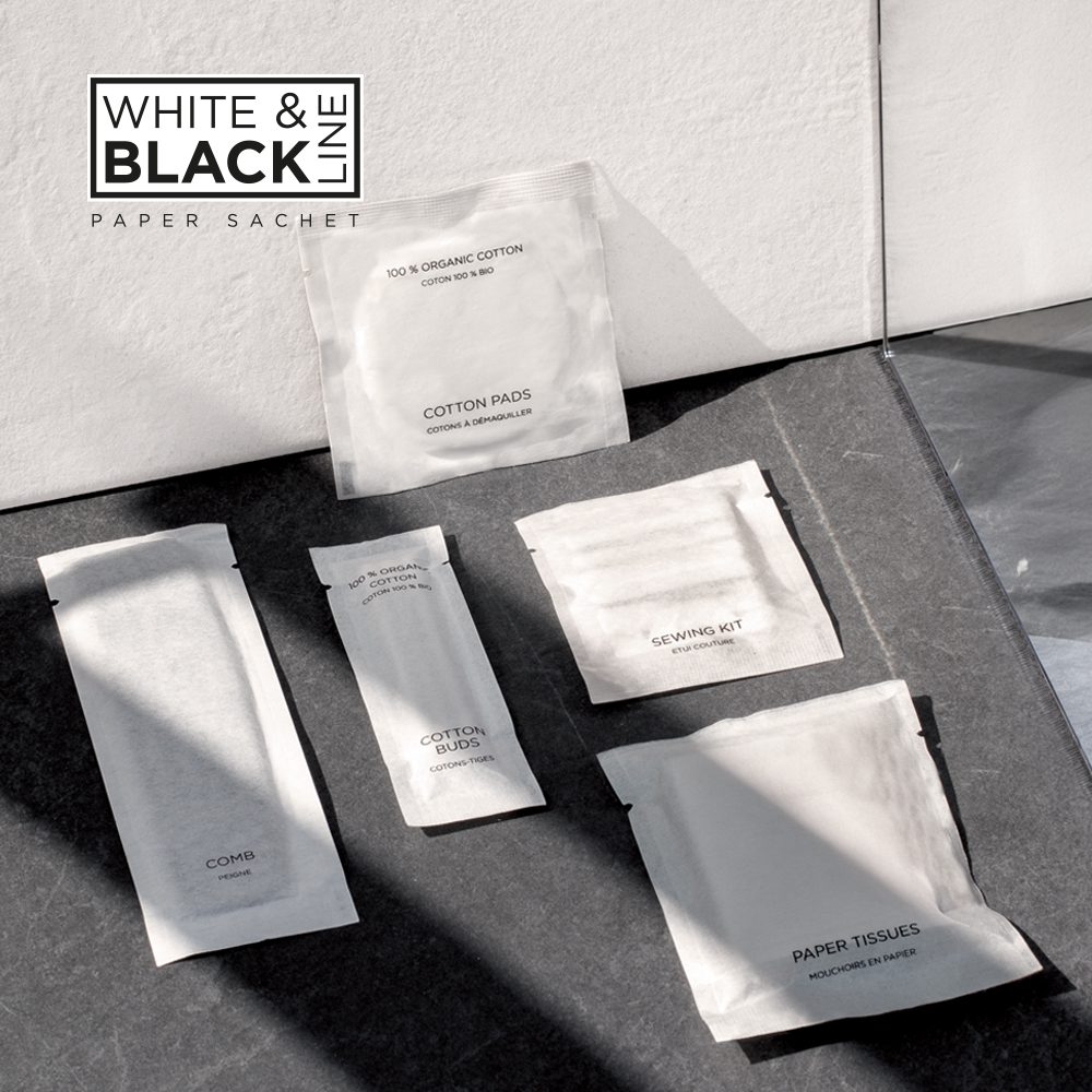 Five white sachets and packets arranged on a dark surface, featuring items like cotton pads, a serving kit, a comb, and paper tissues, with a logo reading "WHITE & BLACK LINE PAPER SACHET" in the corner.