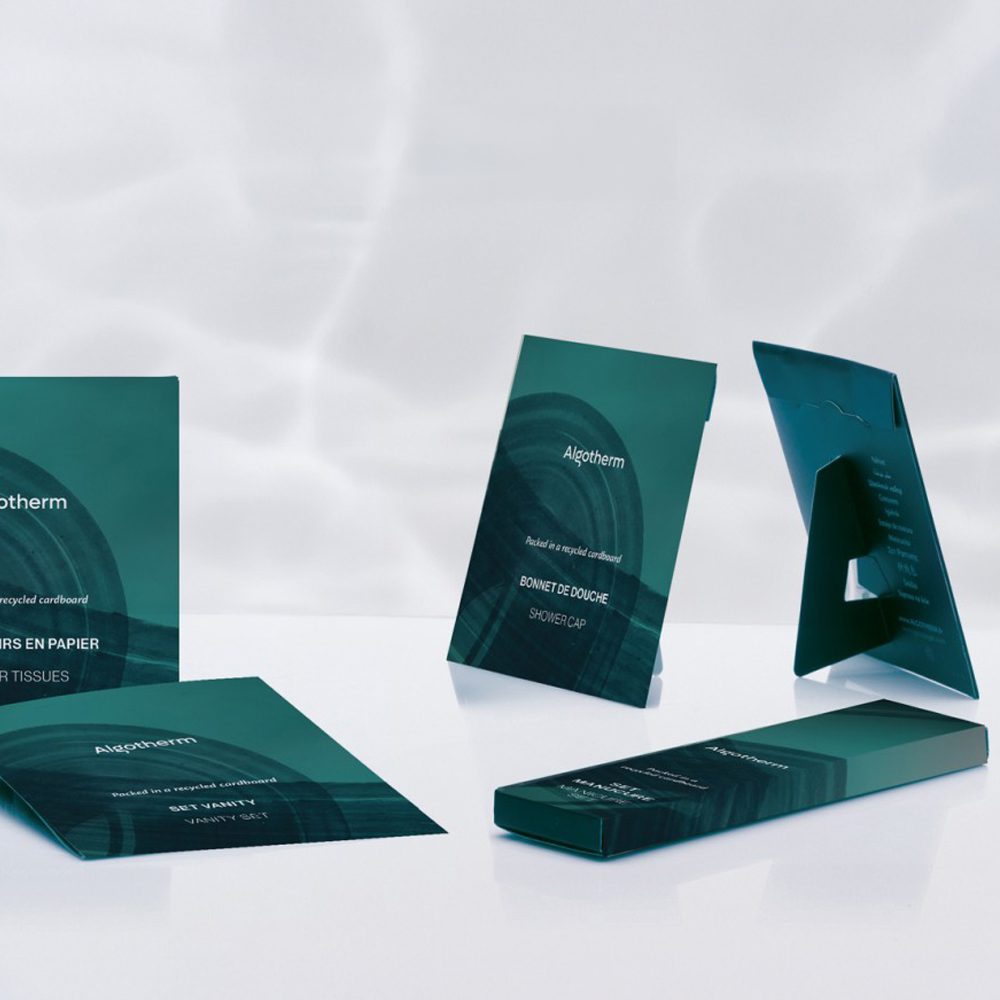 A collection of green packaging designs for Algotherm products, including tissue paper and a shower cap, displayed against a light background.