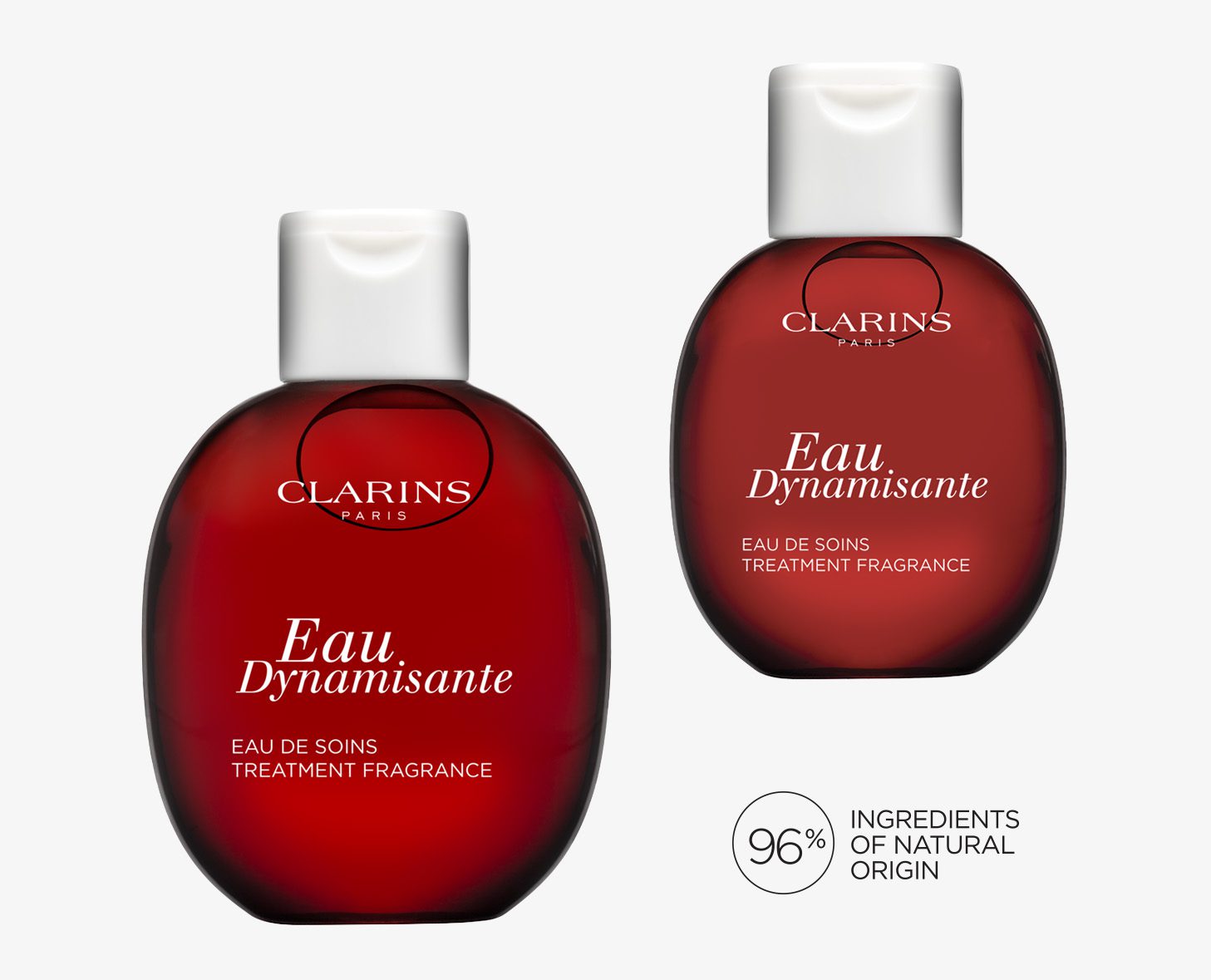 Two bottles of Clarins Eau Dynamisante treatment fragrance, featuring a round, red design with white text. One bottle shows the front label and the other is slightly turned, accompanied by a note about 96% natural ingredients.