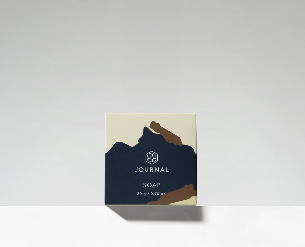 A minimalist soap box featuring abstract brown and cream shapes on a beige background, with the word "SOAP" and the brand name "JOURNAL" prominently displayed.