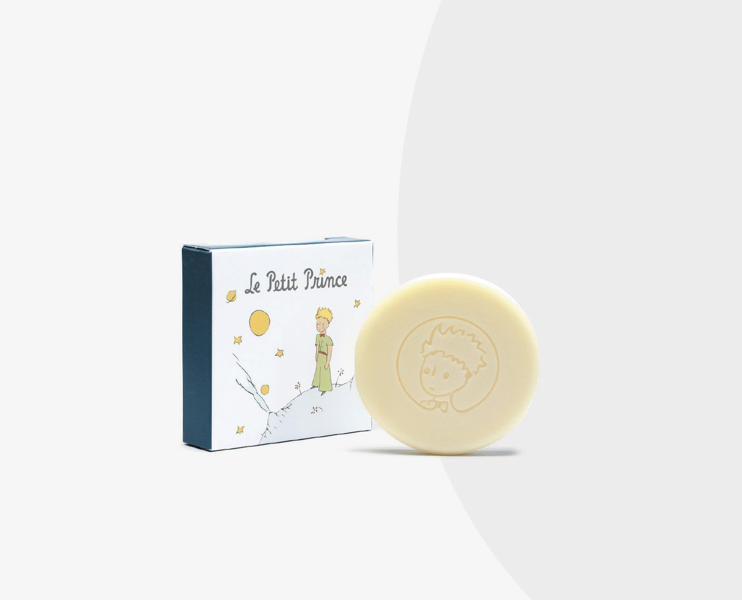 A bar of soap featuring an embossed image of a character with spiky hair, accompanied by a decorative box illustrating the same character standing on a hill with stars and planets.