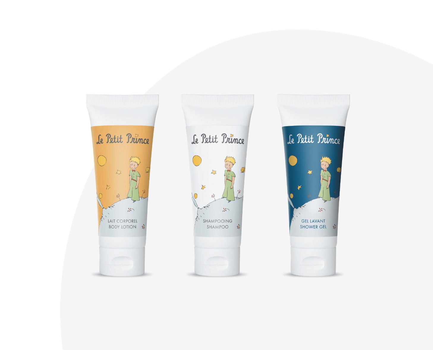 Three tubes of "Le Petit Prince" skincare products: a body lotion in a yellow tube, a shampoo in a white tube, and a shower gel in a dark blue tube, each featuring illustrations of a young boy with stars.
