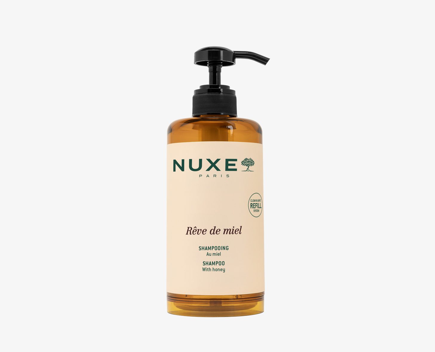 A bottle of NUXE Rêve de Miel shampoo with a pump dispenser, featuring a honey-themed design and a refillable label. The bottle is amber in color with a cream-colored label.