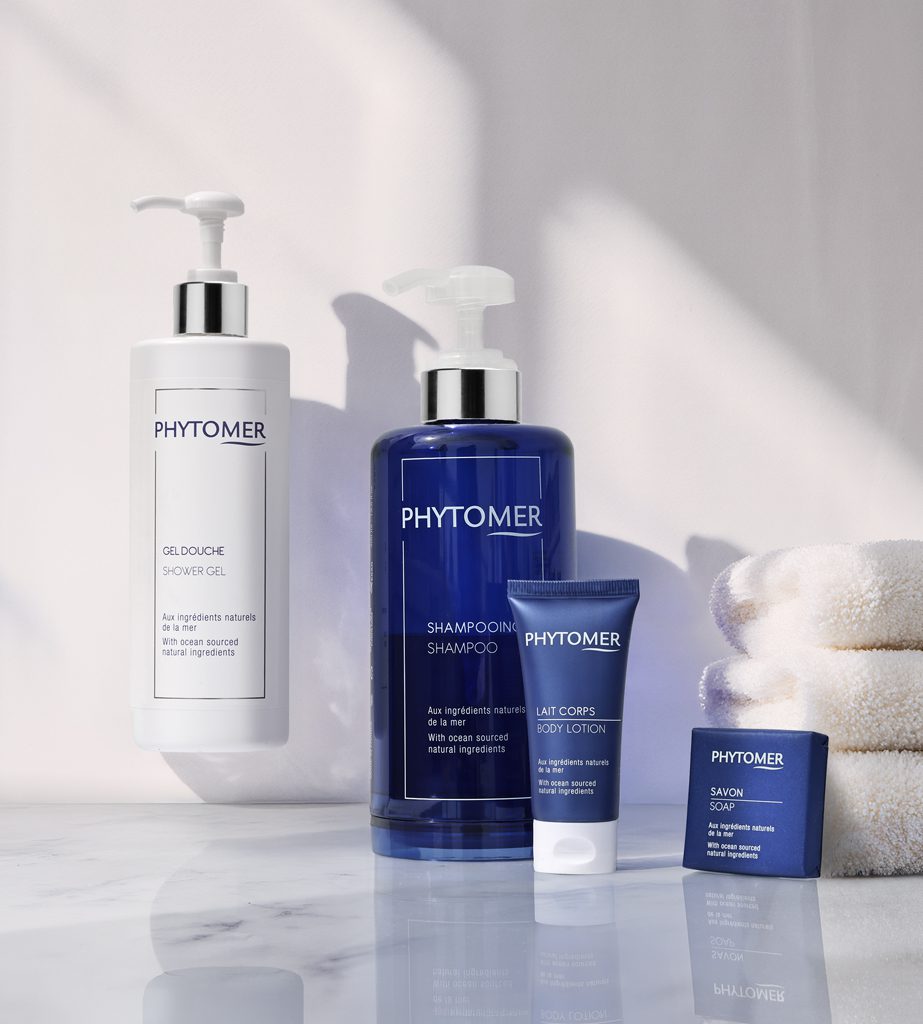 A collection of Phytomer skincare products including a shower gel, shampoo, body lotion, and soap, displayed on a marble surface with white towels.