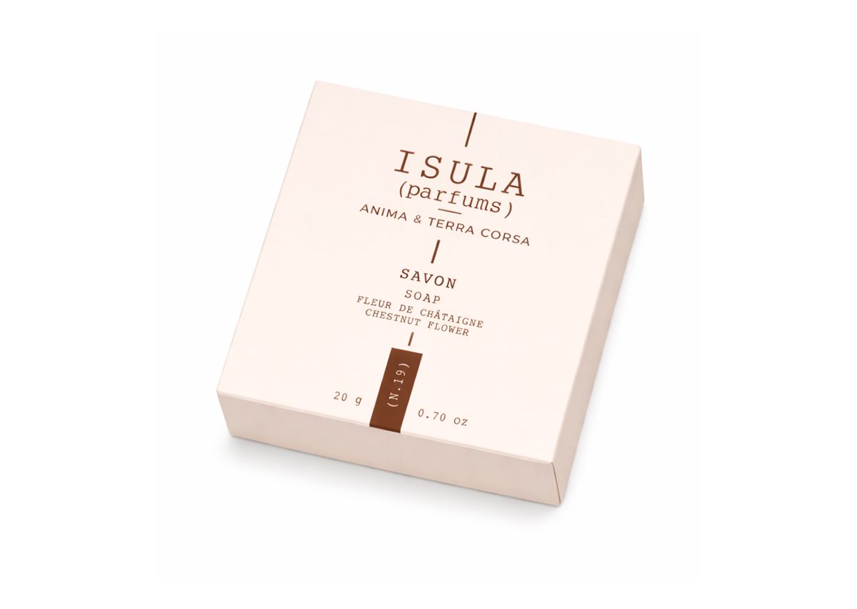 A light pink soap box labeled "ISULA (parfums) ANIMA & TERRA CORSA" with the word "SAVON" and "FLEUR DE CHâTAIGNER" printed on it, containing 20 grams of product.