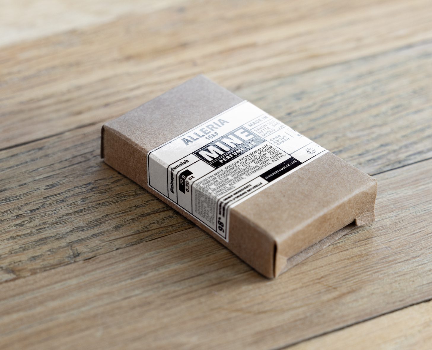 A cardboard box with a minimalist black and white label, resting on a wooden surface. The label features text that includes the brand name "Alleria" and mentions "MINE."