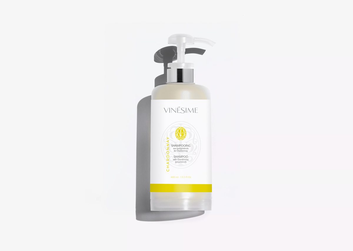 A bottle of Vinésime Chardonnay shampoo with a pump dispenser, featuring a sleek design and a white label with yellow accents. The shampoo is displayed against a plain white background.