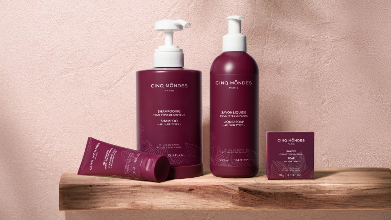 Cinq Mondes Paris skincare products (shampoo, liquid soap, cleansing gel, and bar soap) displayed on a wooden shelf
