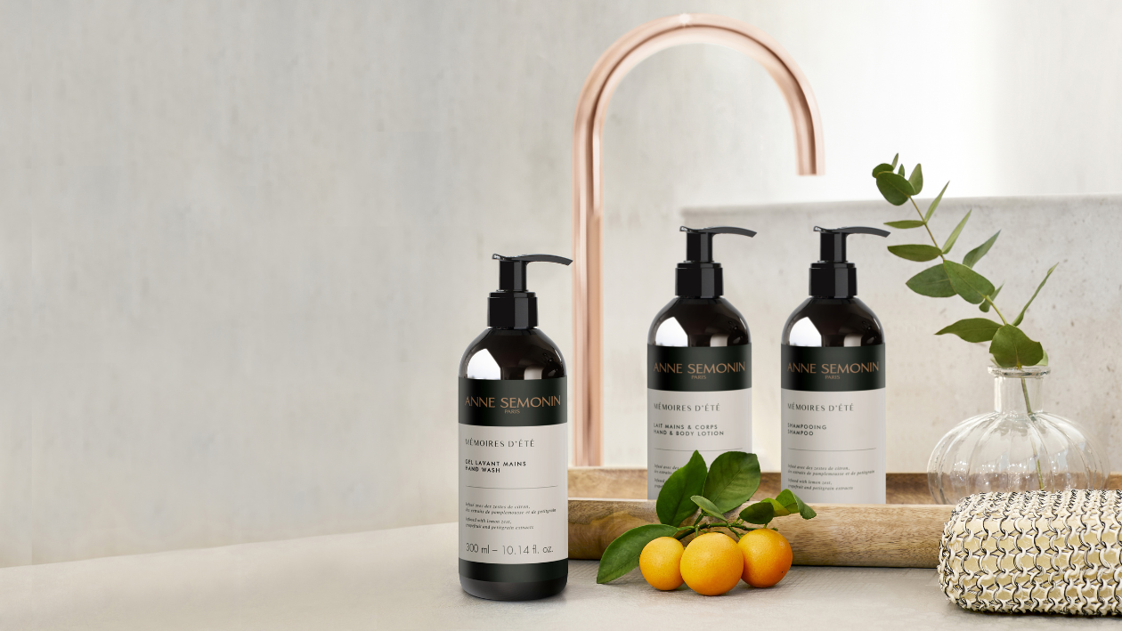 Anne Semonin "Mémoires d’Été" handzeep, bodylotion en shampoo, uitgestald bij een wastafel met citrusvruchten en groen.