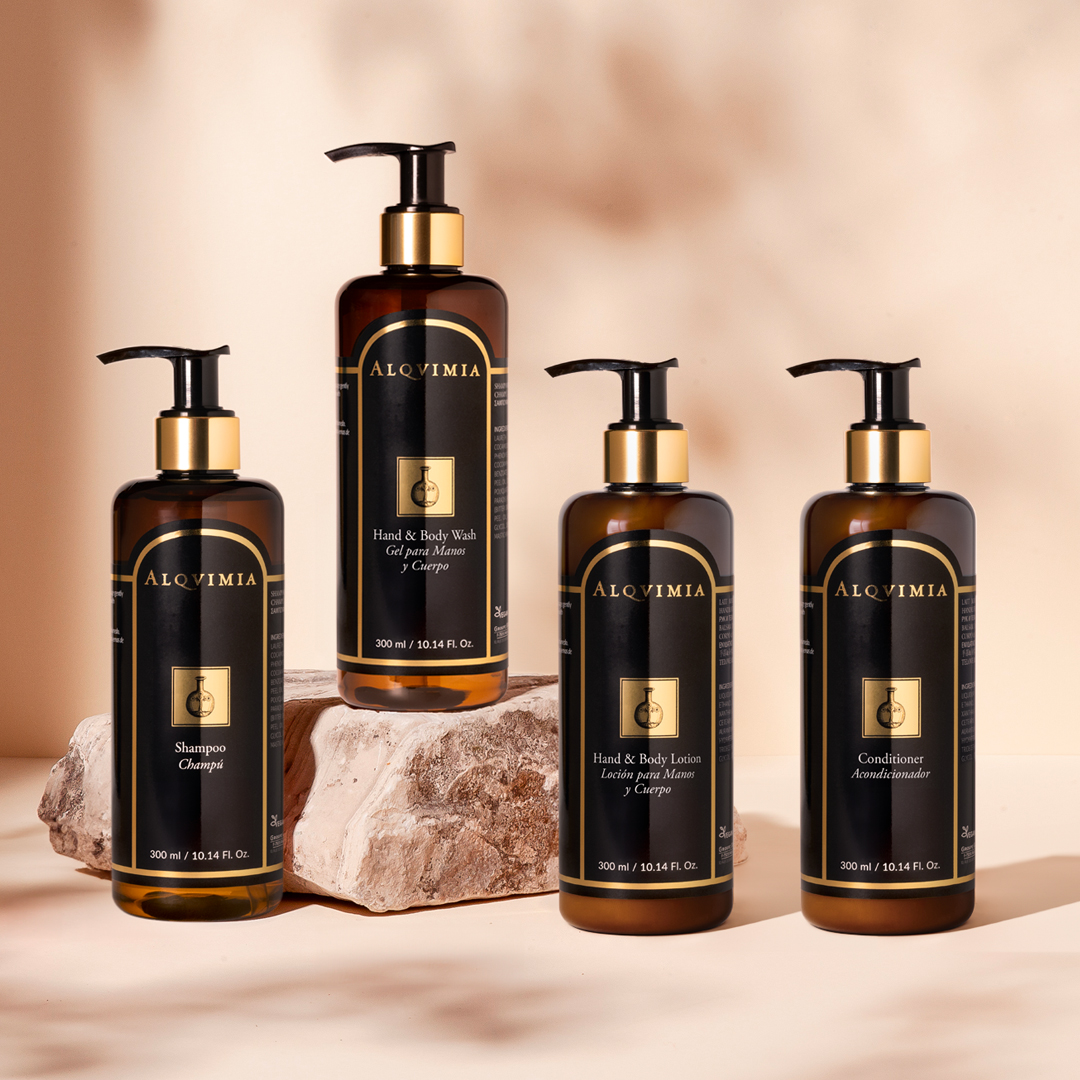 Alqvimia spa range including shampoo, hand and body wash, lotion, and conditioner in pump bottles displayed with natural stone