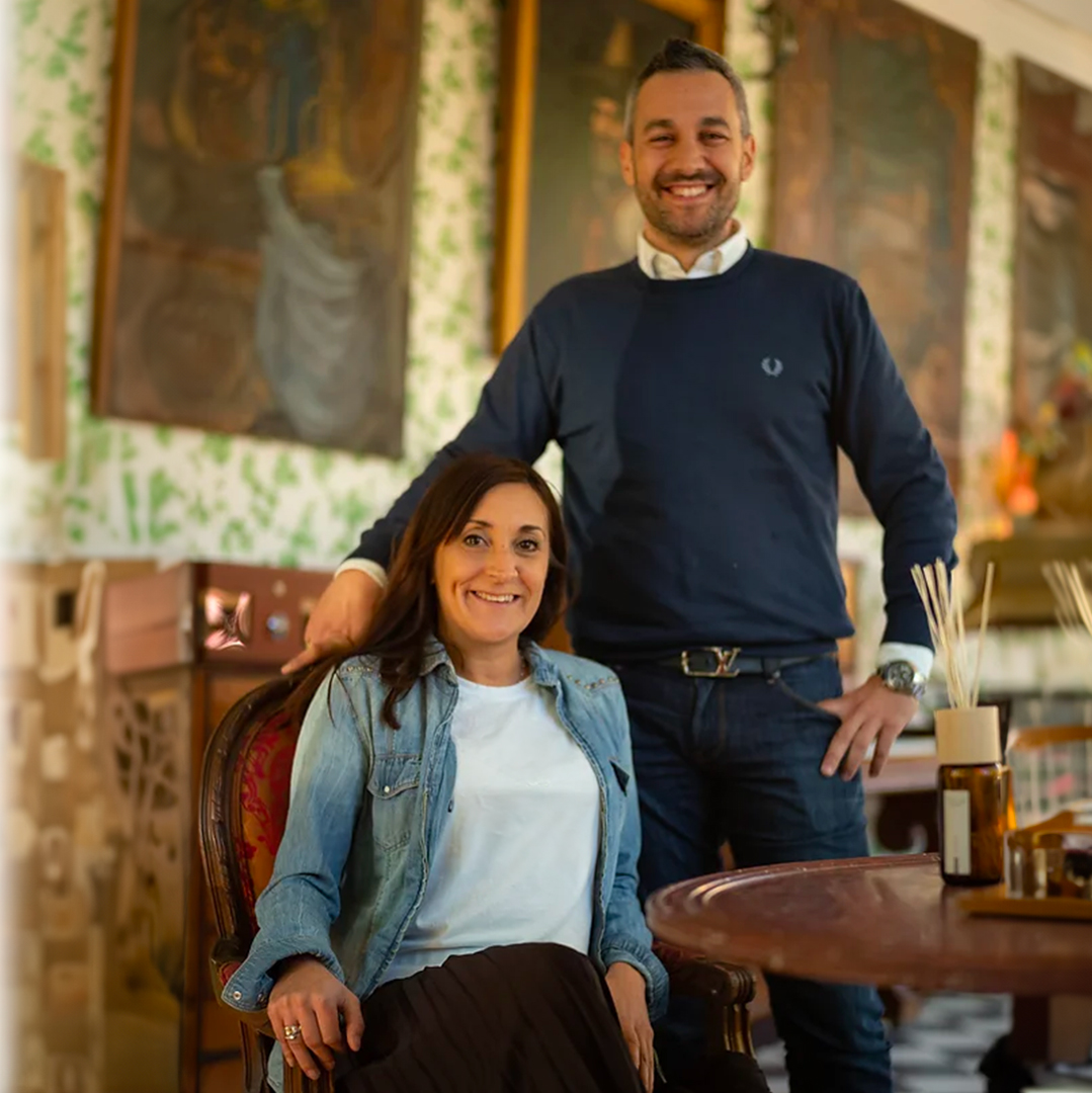 Two people smiling indoors in a warm, decorative setting, representing the Isula brand story