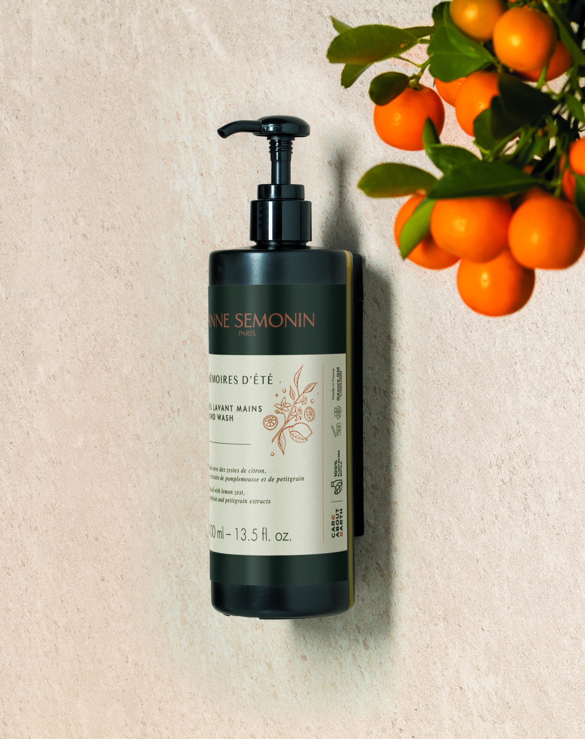 Anne Semonin "Mémoires d’Été" handzeepflesje aan de muur, gestyled met verse citrusvruchten aan een tak.