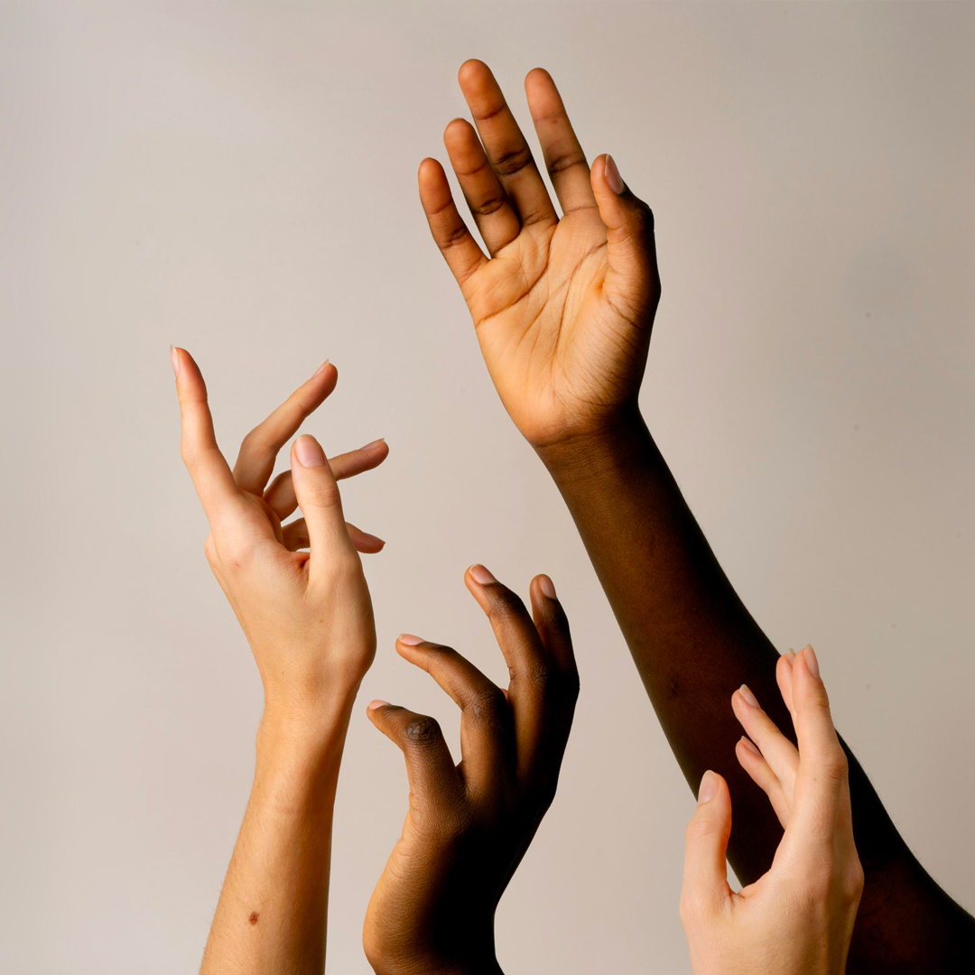 Diverse hands raised against neutral background