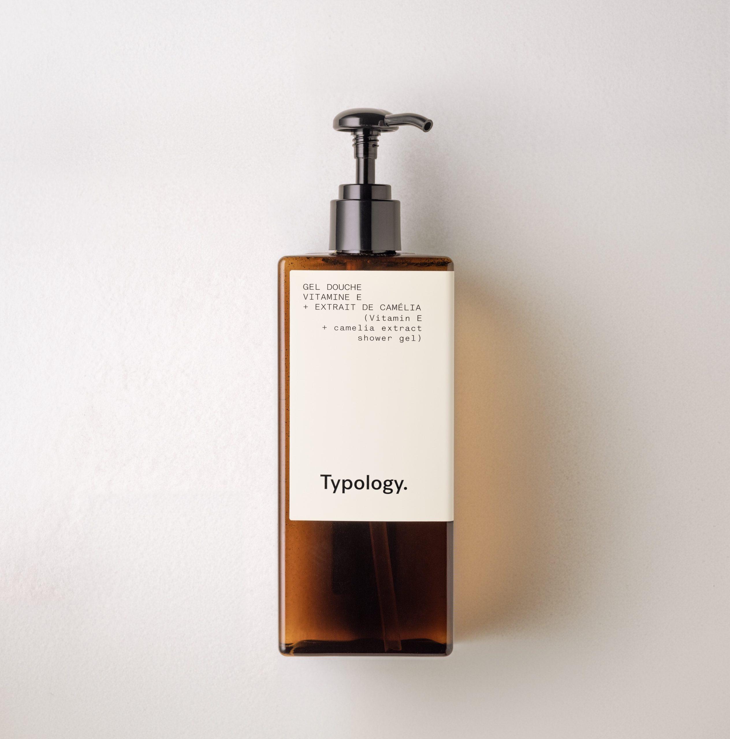 Typology shower gel pump bottle with amber design on neutral background