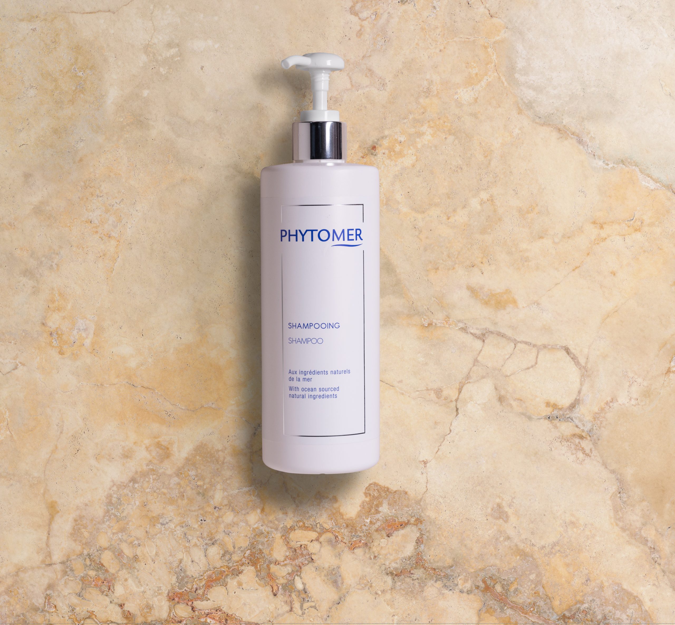 Phytomer Flacon de shampoing Phytomer muni d'un distributeur à pompe, présenté sur un fond en pierre texturée.