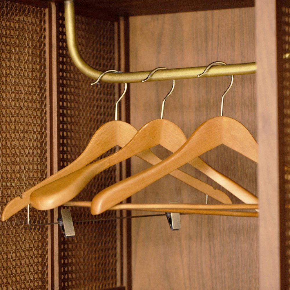 Wooden clothes hangers hanging inside a hotel wardrobe.
