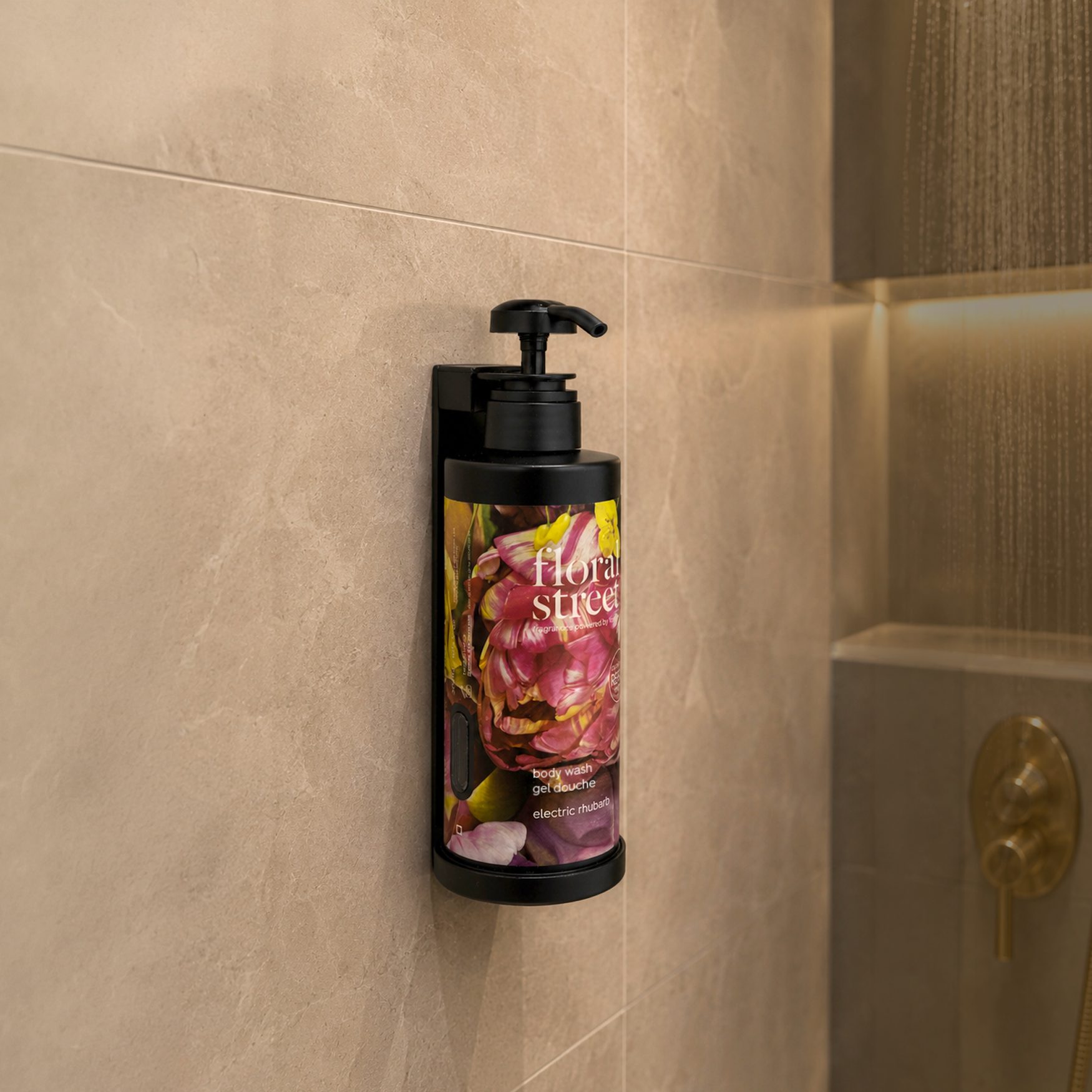 Floral Street Electric Rhubarb body wash refill bottle mounted in a minimalist shower with gold fixtures and built-in shelf detail.
