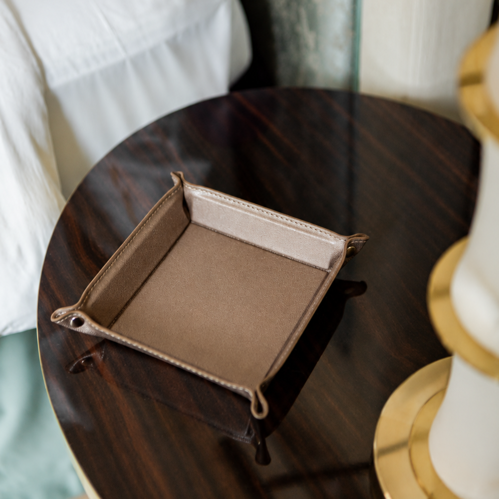 Leather valet tray displayed on a dark wooden bedside table.