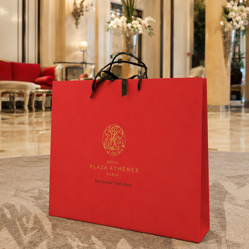 Luxury Plaza Athénée shopping bag displayed in the hotel lobby.