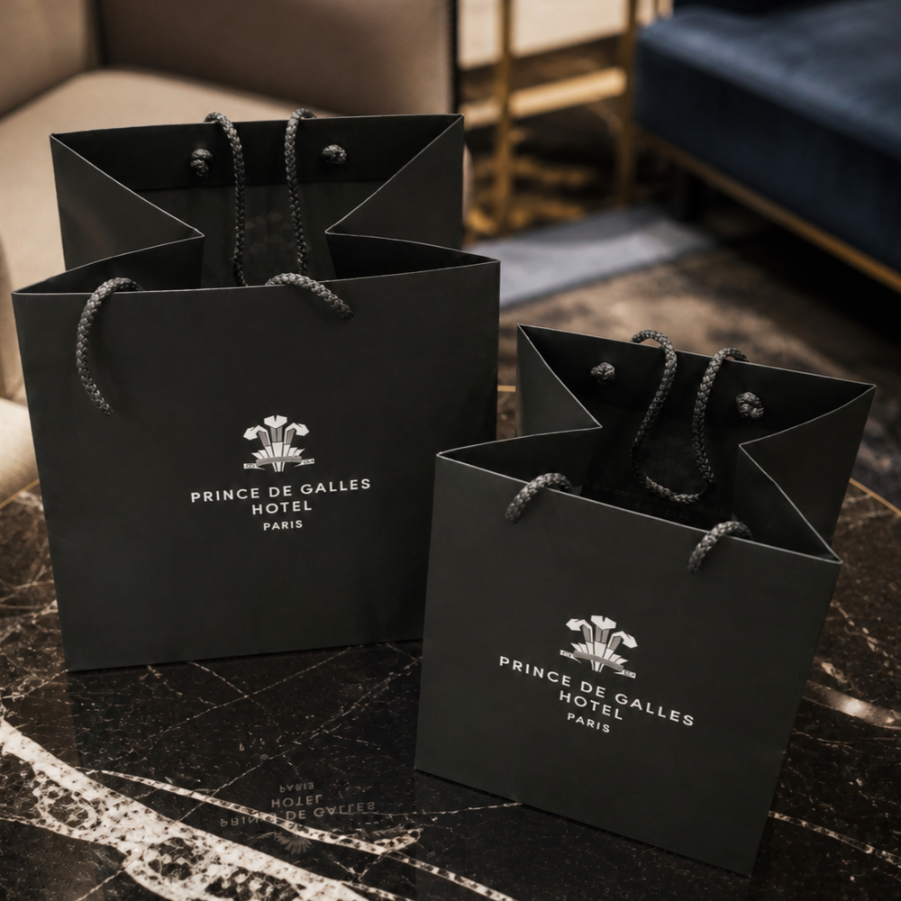 Elegant Prince de Galles shopping bags presented in a hotel lounge.