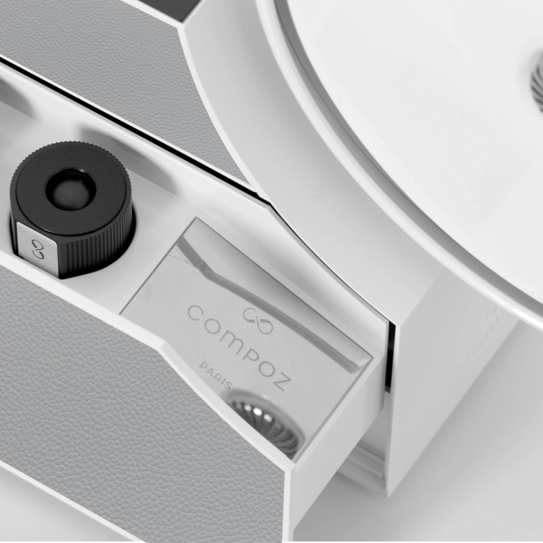 Detail of the Compoz fragrance creation system with a scent cartridge and branded accessory compartment in a premium white design.