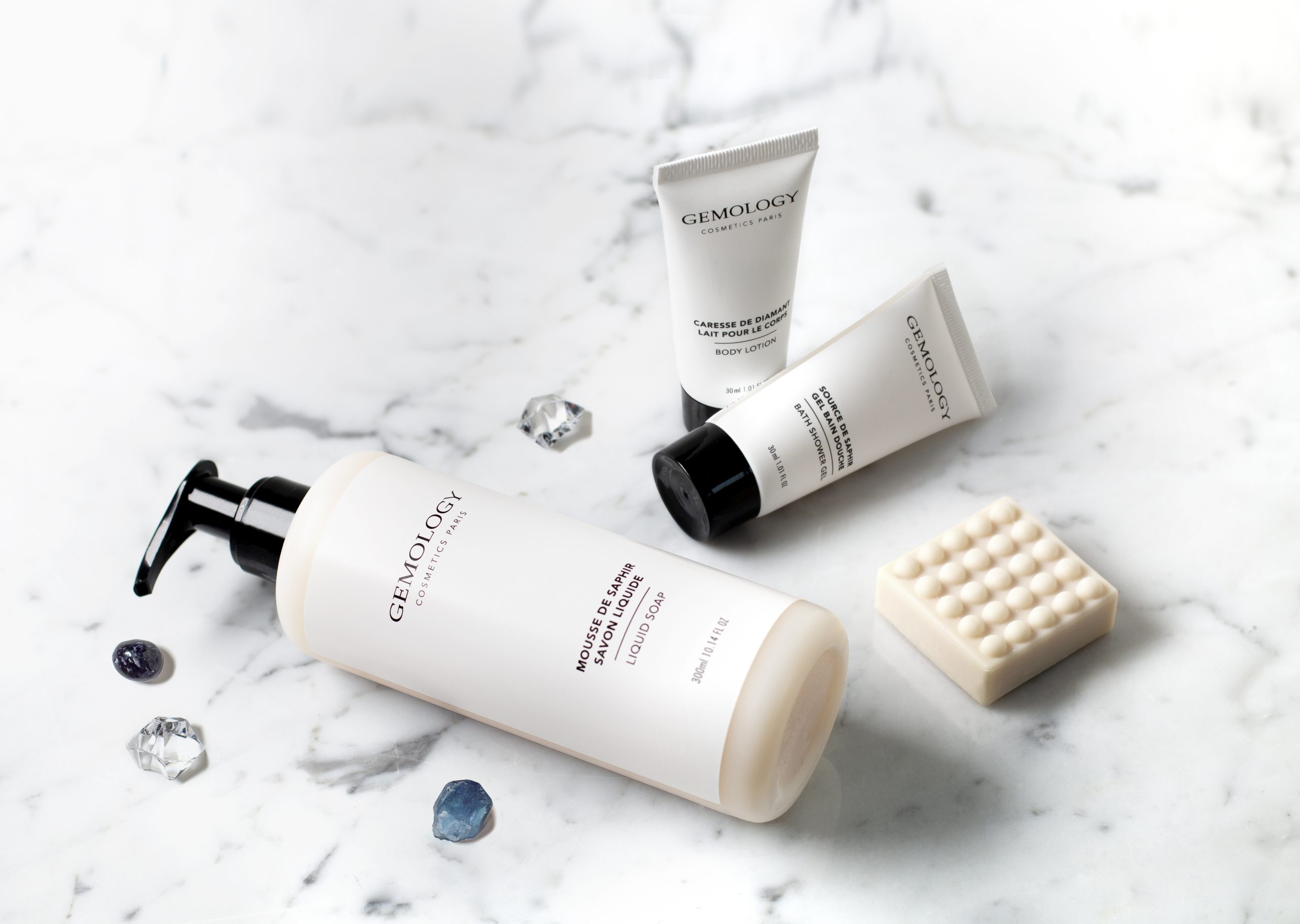 Gemology amenities displayed on a marble surface with gemstones and a massage soap bar.