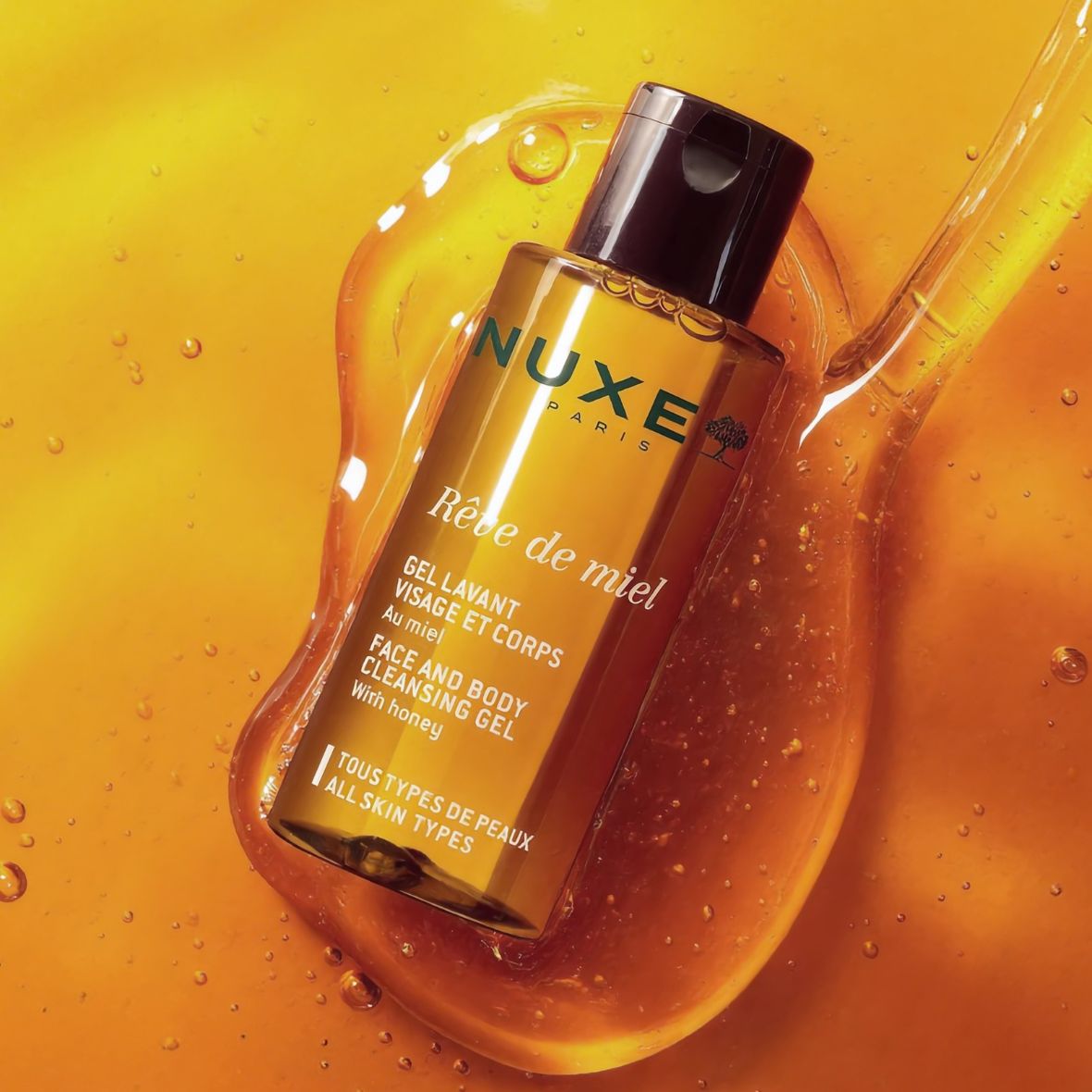 NUXE Rêve de Miel Face and Body Cleansing Gel with honey on golden honey background.
